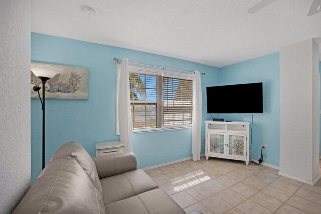 living room featuring a ceiling fan, light tile patterned flooring, and baseboards