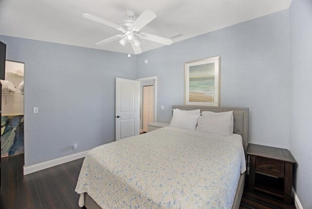 bedroom featuring dark wood-type flooring, a spacious closet, baseboards, and a ceiling fan