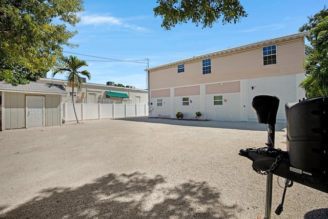 rear view of house with fence, an outdoor structure, and a storage unit