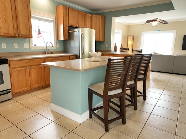 1590 Dolphin Dr, Marathon, FL 33050 - kitchen with freestanding refrigerator, ornamental molding, plenty of natural light, a breakfast bar, and light countertops