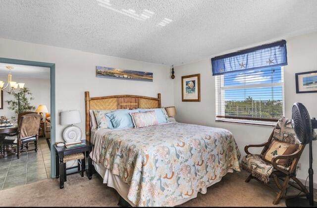 2000 Coco Plum Dr Unit 603, Marathon, FL 33050 - bedroom featuring a chandelier, a textured ceiling, and carpet floors