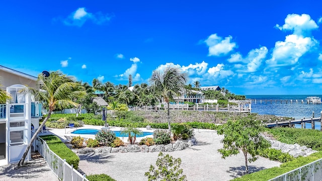 surrounding community with a water view, fence, and a pool