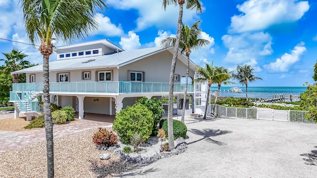 view of front of house featuring a water view, a gate, fence, decorative driveway, and stucco siding