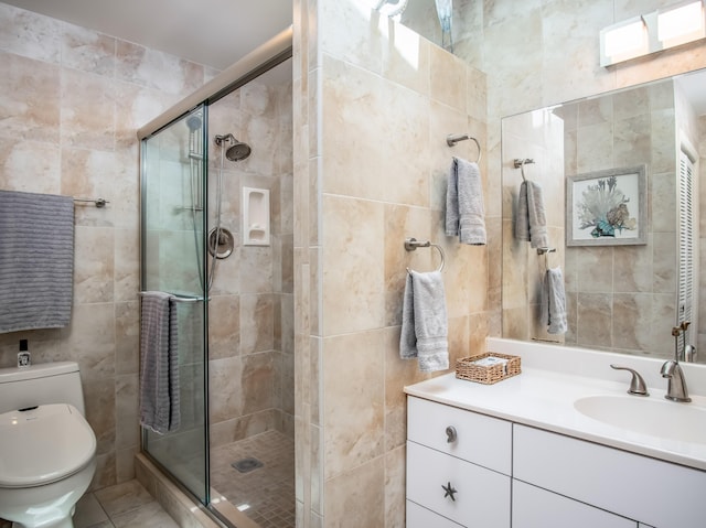 bathroom with toilet, a stall shower, tile walls, and vanity