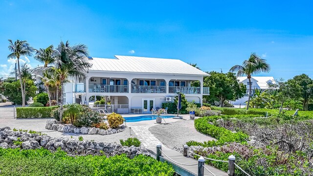 back of property with a patio, a balcony, an outdoor pool, french doors, and stucco siding