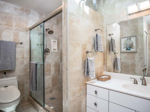 full bathroom featuring toilet, tile walls, a shower stall, and vanity