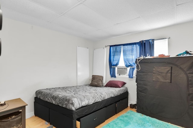 bedroom with cooling unit, baseboards, and wood finished floors