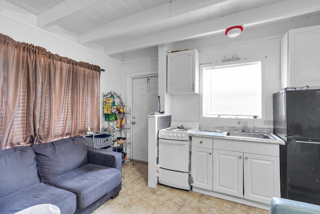 kitchen with a sink, white range oven, white cabinets, and freestanding refrigerator