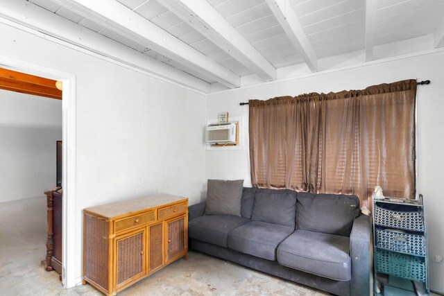 living area with an AC wall unit, concrete flooring, and beam ceiling