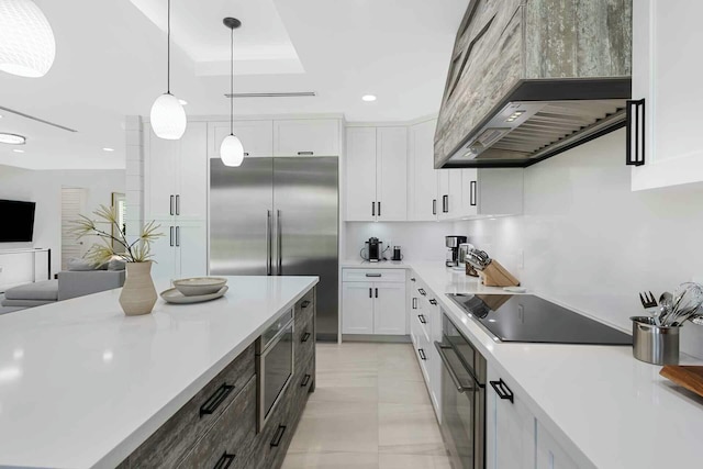 kitchen featuring built in appliances, pendant lighting, light countertops, decorative backsplash, and white cabinets