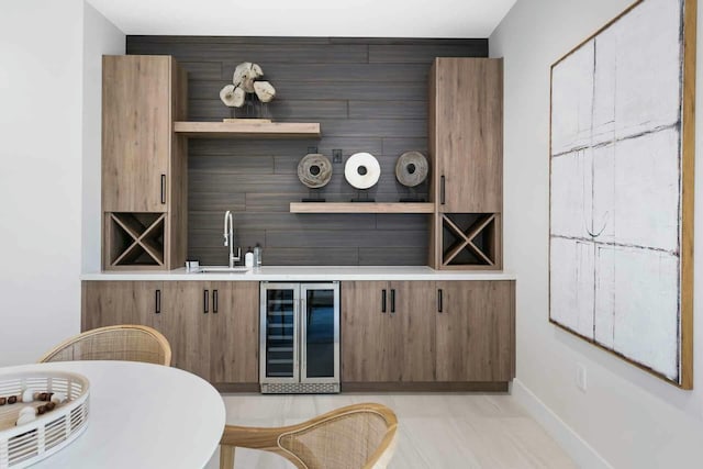 bar with baseboards, wine cooler, light tile patterned floors, bar, and a sink
