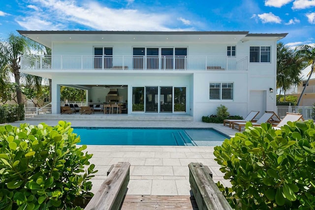 back of house with an outdoor pool, a patio, a balcony, and fence