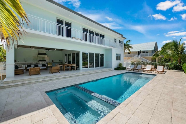 view of pool with a ceiling fan, exterior kitchen, an outdoor living space, a pool with connected hot tub, and a patio area