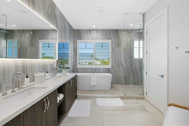bathroom featuring visible vents, a sink, double vanity, a freestanding bath, and walk in shower