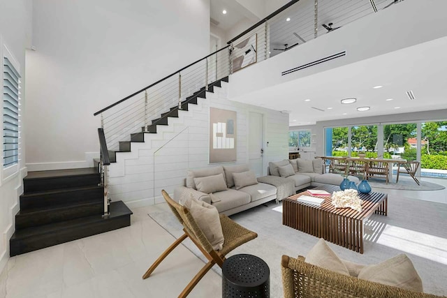 living room with recessed lighting, a towering ceiling, and stairs