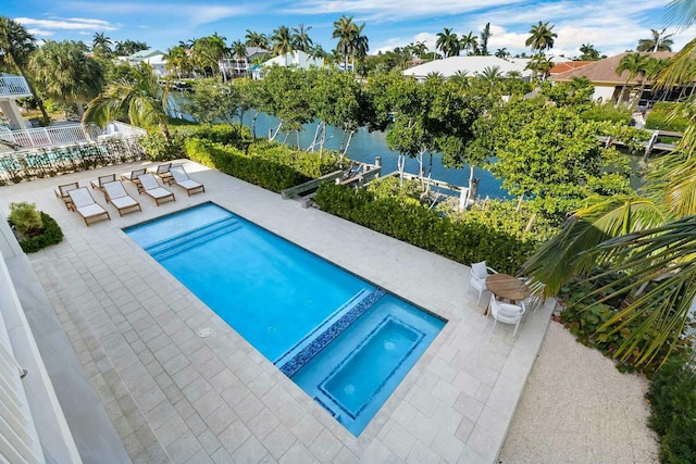 view of pool with a water view, fence, a pool with connected hot tub, and a patio area