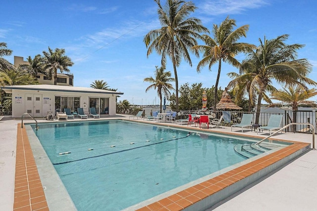 community pool with a patio area and fence