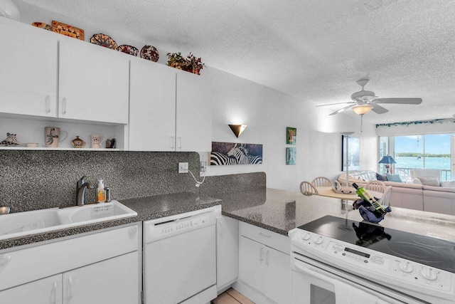 kitchen with ceiling fan, a textured ceiling, white appliances, a sink, and white cabinets