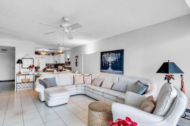 living room with light tile patterned flooring, ceiling fan, a textured ceiling, and decorative columns