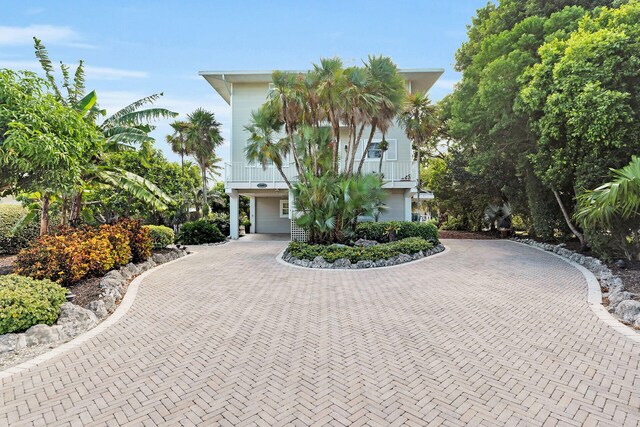 raised beach house featuring decorative driveway and a balcony