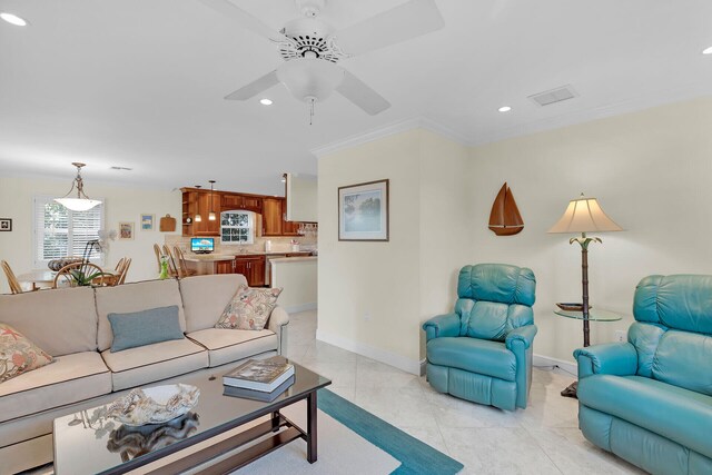 living area featuring light tile patterned floors, visible vents, crown molding, and baseboards