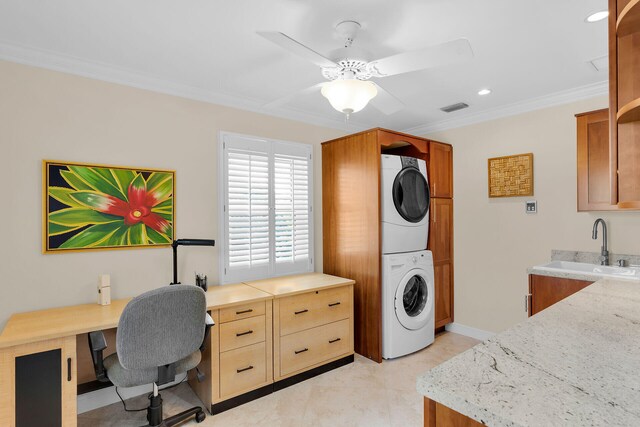 washroom featuring a ceiling fan, laundry area, a sink, stacked washer / drying machine, and crown molding