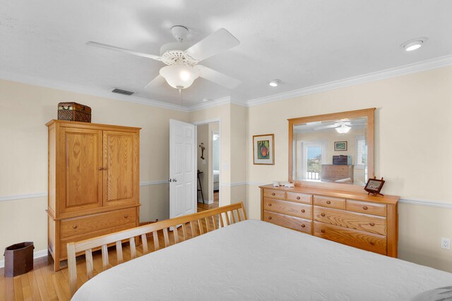 bedroom featuring crown molding, wood finished floors, visible vents, and ceiling fan