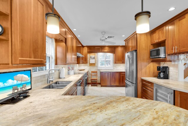 kitchen with a sink, stainless steel appliances, wine cooler, under cabinet range hood, and brown cabinets