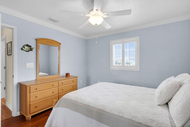 bedroom with visible vents, crown molding, a ceiling fan, and dark wood-style flooring