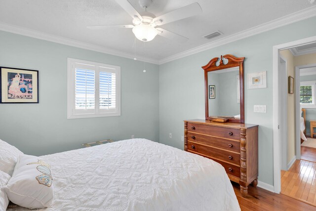 bedroom featuring hardwood / wood-style floors, crown molding, multiple windows, and visible vents