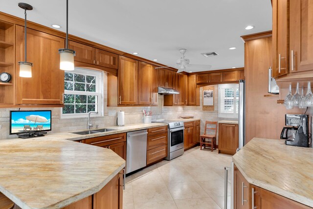 kitchen featuring visible vents, a peninsula, a sink, under cabinet range hood, and appliances with stainless steel finishes