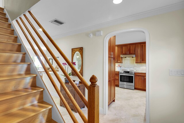 stairs featuring visible vents, tile patterned floors, baseboards, ornamental molding, and arched walkways