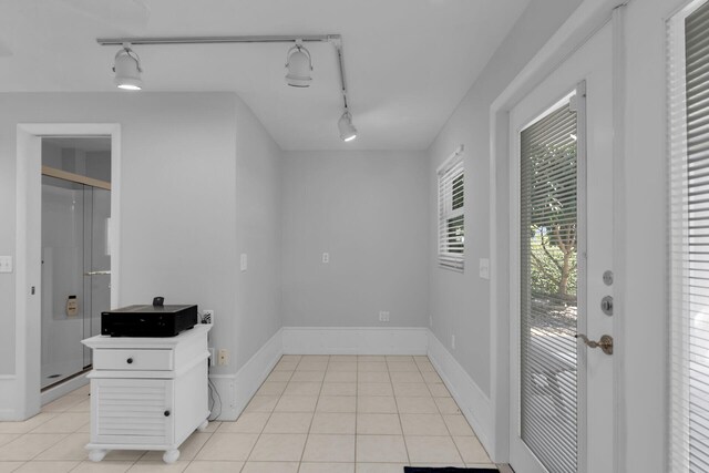 interior space featuring rail lighting, light tile patterned floors, and baseboards