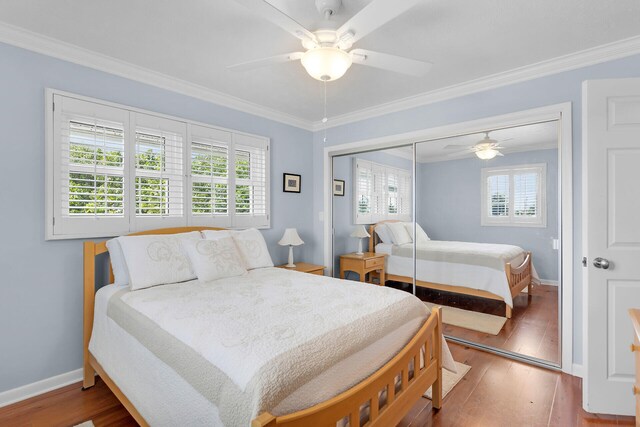 bedroom featuring ornamental molding, wood finished floors, a closet, baseboards, and ceiling fan