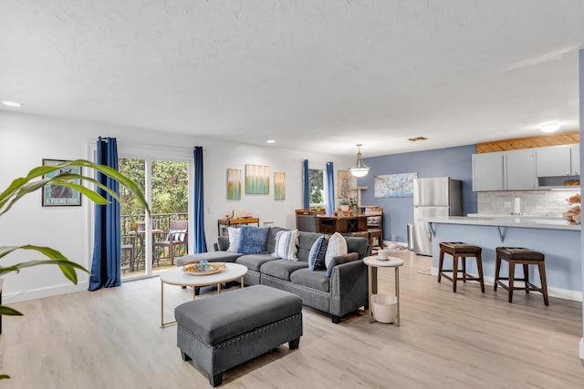 living area featuring baseboards, light wood-style floors, and recessed lighting