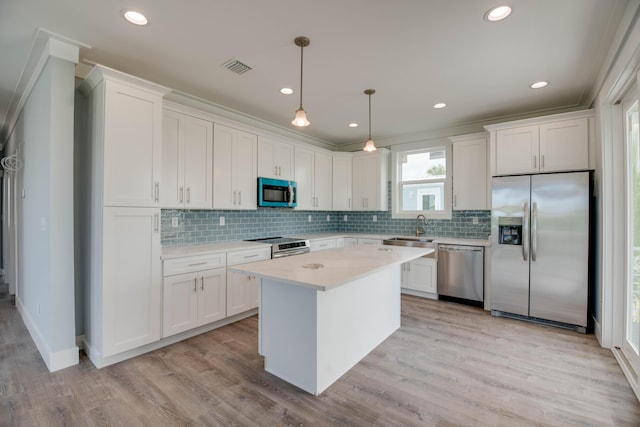 335 Pirates Rd, Little Torch, FL 33042 - kitchen featuring stainless steel appliances, white cabinets, backsplash, light wood-style floors, and a kitchen island