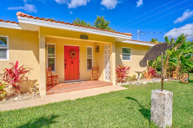 30985 Hibiscus Dr, Big Pine, FL 33043 - view of exterior entry featuring stucco siding, a yard, and a tile roof