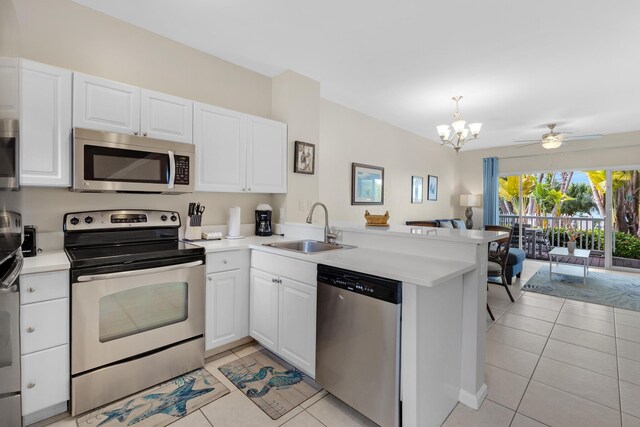 5081 Sunset Village Dr, Duck, FL 33050 - kitchen with appliances with stainless steel finishes, a sink, light tile patterned floors, and a peninsula