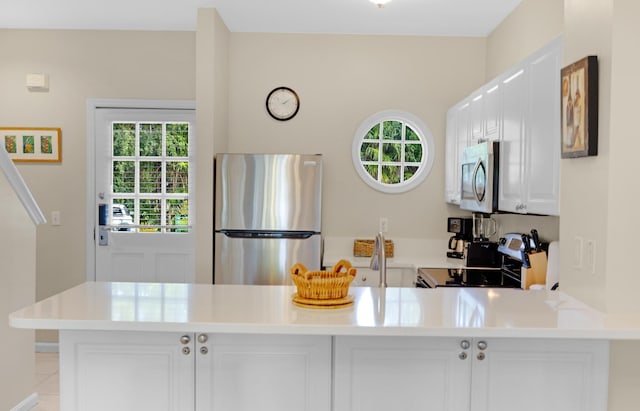 5081 Sunset Village Dr, Duck, FL 33050 - kitchen with stainless steel appliances, plenty of natural light, white cabinets, and a peninsula
