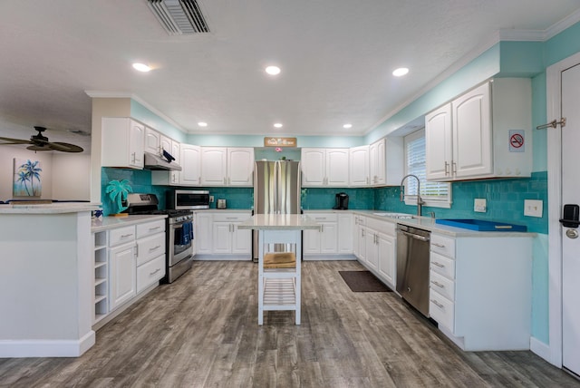 kitchen featuring visible vents, wood finished floors, stainless steel appliances, under cabinet range hood, and a sink