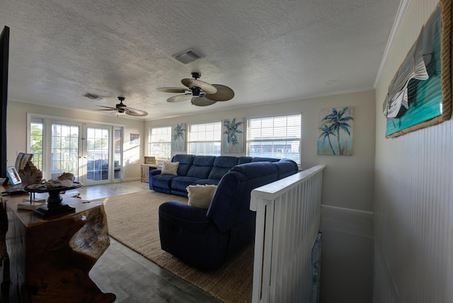 living room with ornamental molding, visible vents, a textured ceiling, and baseboards