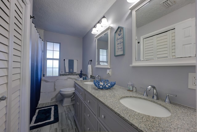 bathroom featuring a textured ceiling, plenty of natural light, a sink, and visible vents