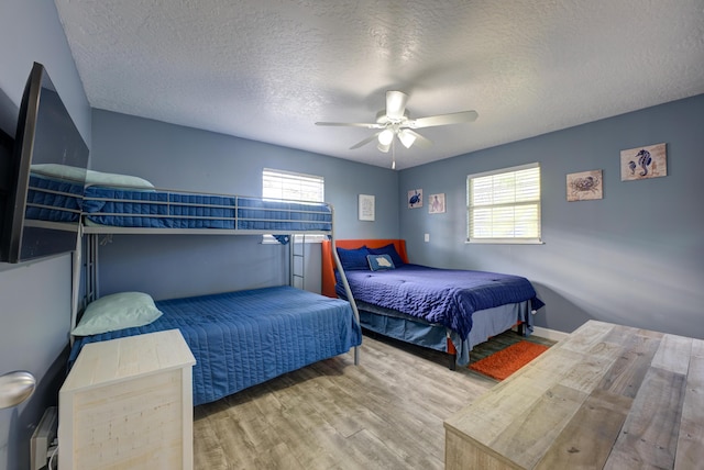 bedroom with multiple windows, a textured ceiling, and wood finished floors