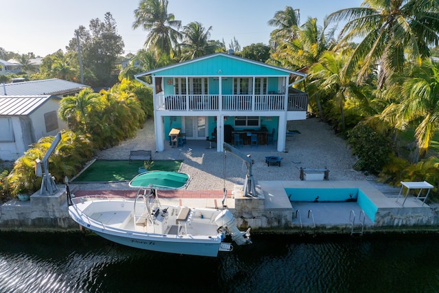 rear view of property with a water view, a patio area, boat lift, and french doors