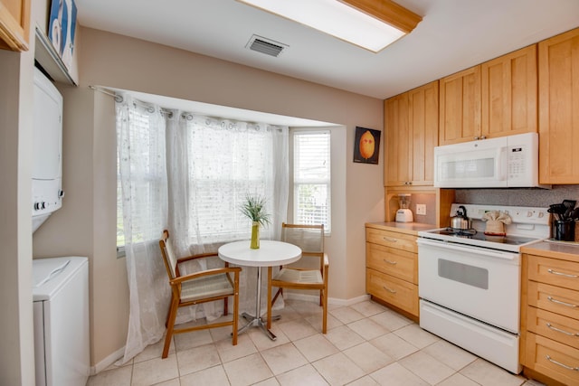 kitchen with white appliances, baseboards, light countertops, light brown cabinetry, and light tile patterned floors