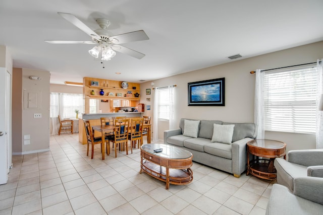 living room with healthy amount of natural light, light tile patterned flooring, and a ceiling fan