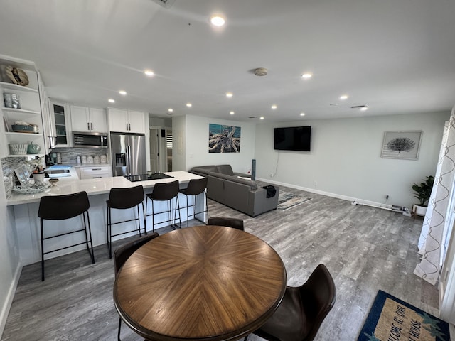 dining space featuring baseboards, wood finished floors, and recessed lighting