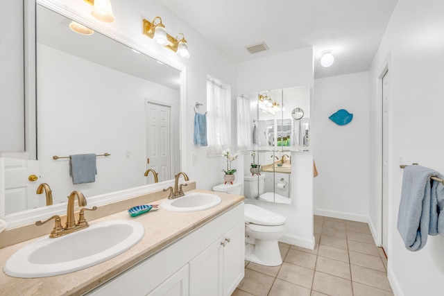 bathroom with double vanity, toilet, a sink, and tile patterned floors