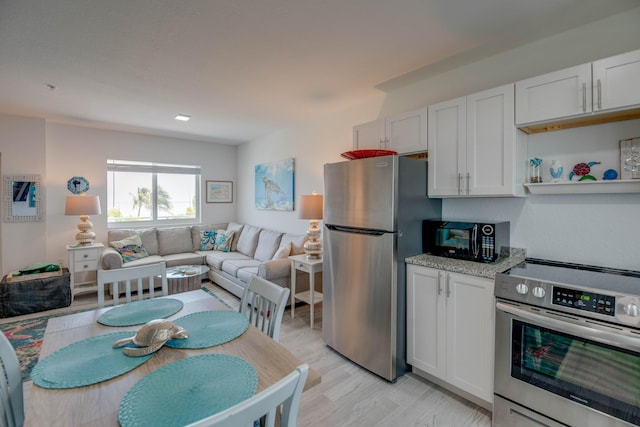 10877 Overseas Hwy Unit 81, Marathon, FL 33050 - kitchen with stainless steel appliances, open floor plan, white cabinetry, and light wood finished floors