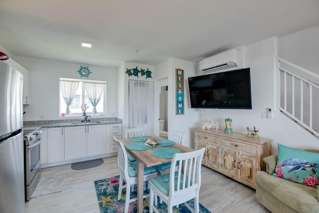 10877 Overseas Hwy Unit 81, Marathon, FL 33050 - kitchen featuring an AC wall unit, appliances with stainless steel finishes, a sink, light stone countertops, and white cabinets